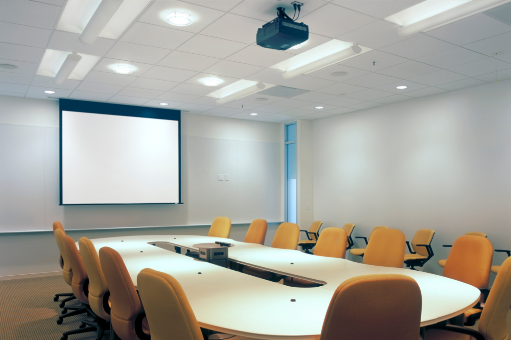 Professional audio visual system in a classroom-style meeting room with projector, screen, and collaboration technology